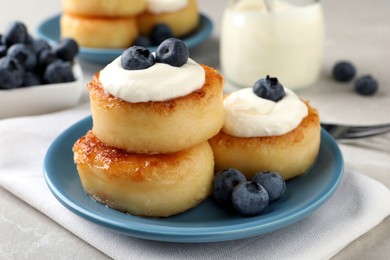 Photo of Delicious cottage cheese pancakes with blueberries, honey and sour cream on light table, closeup