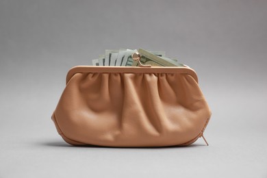 Stylish beige leather purse with dollar banknotes on light grey background
