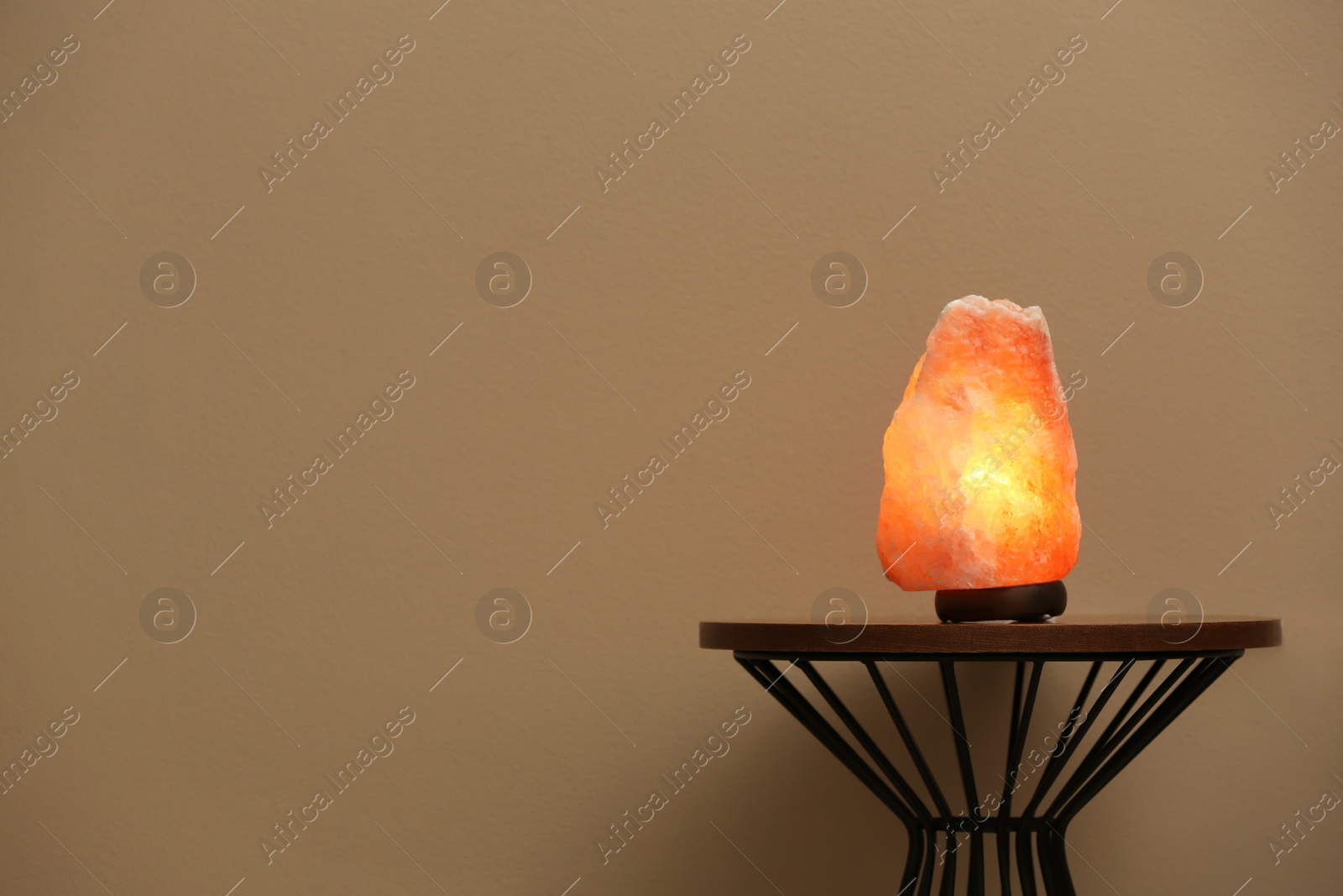 Photo of Himalayan salt lamp on table against  beige background. Space for text