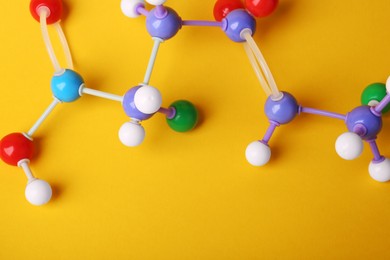 Photo of Structure of molecule on yellow background, top view. Chemical model