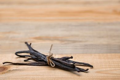 Photo of Aromatic vanilla sticks on wooden background