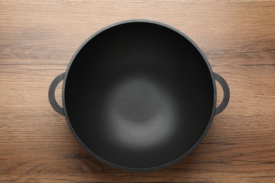 Photo of Empty iron wok on wooden table, top view. Chinese cookware