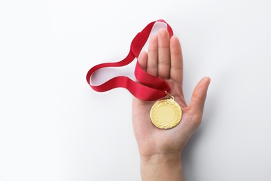 Woman holding gold medal with space for design on white background, top view. Victory concept