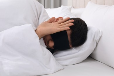 Photo of Man wearing sleeping mask in bed at home