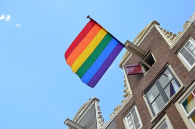 Bright rainbow LGBT pride flag on building facade, low angle view