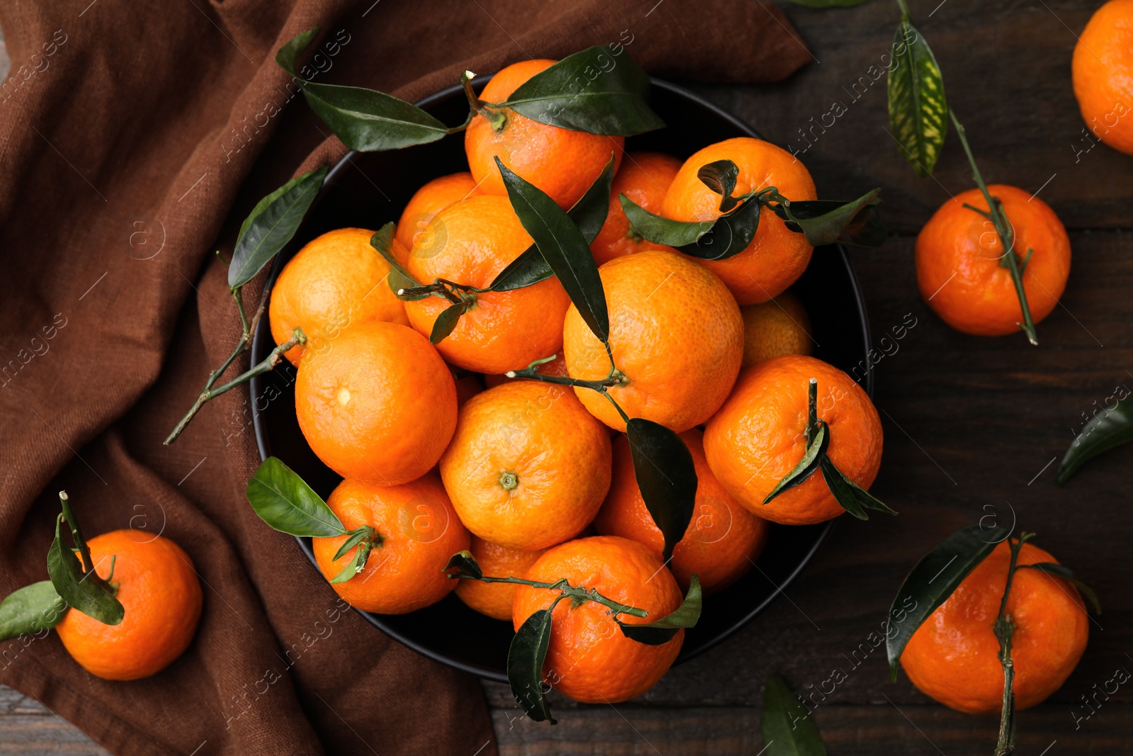 Photo of Fresh ripe tangerines with green leaves on wooden table, flat lay