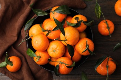 Photo of Fresh ripe tangerines with green leaves on wooden table, flat lay