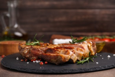 Photo of Pieces of delicious fried meat with rosemary and spices on table, closeup