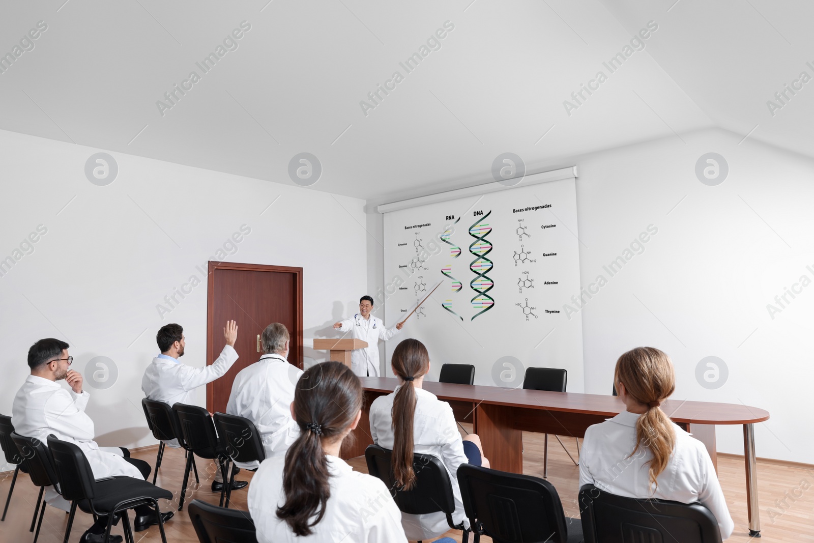 Image of Lecture about difference between RNA and DNA. Professor using projection screen with illustration to audience in conference room