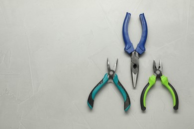 Photo of Different pliers on grey textured table, flat lay. Space for text