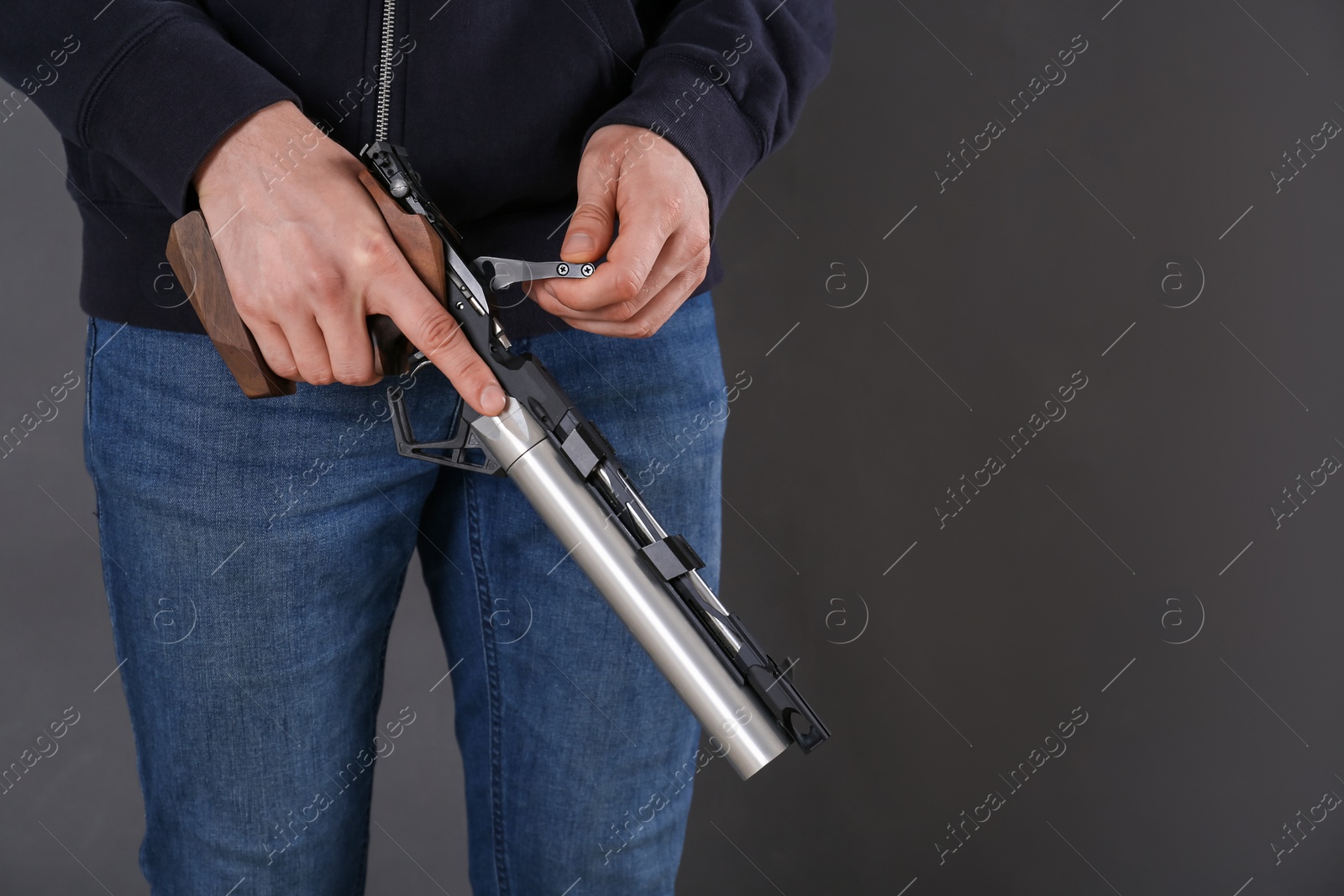 Photo of Gun shooting sport. Man holding standard pistol on dark background, closeup. space for text