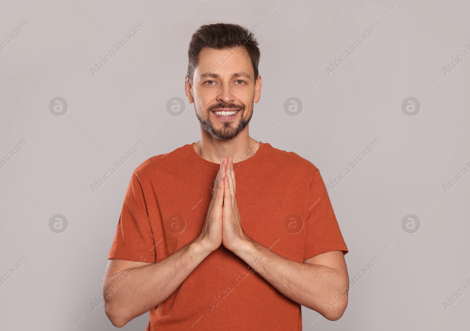 Photo of Man with clasped hands praying on light grey background