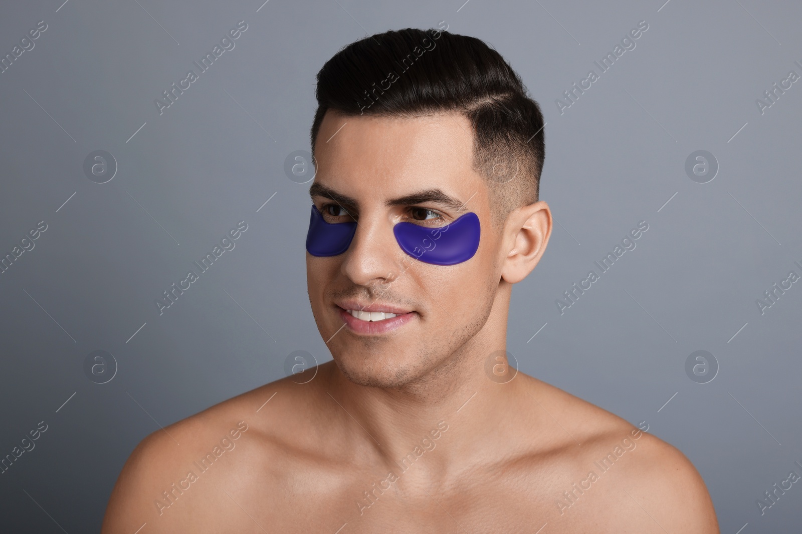 Photo of Man with blue under eye patches on grey background