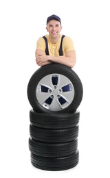 Male mechanic with car tires on white background