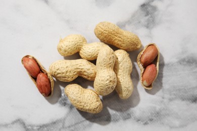 Fresh unpeeled peanuts on white marble table, top view