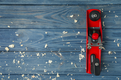Modern jack plane and shavings on blue wooden background, flat lay with space for text. Carpenter's tools