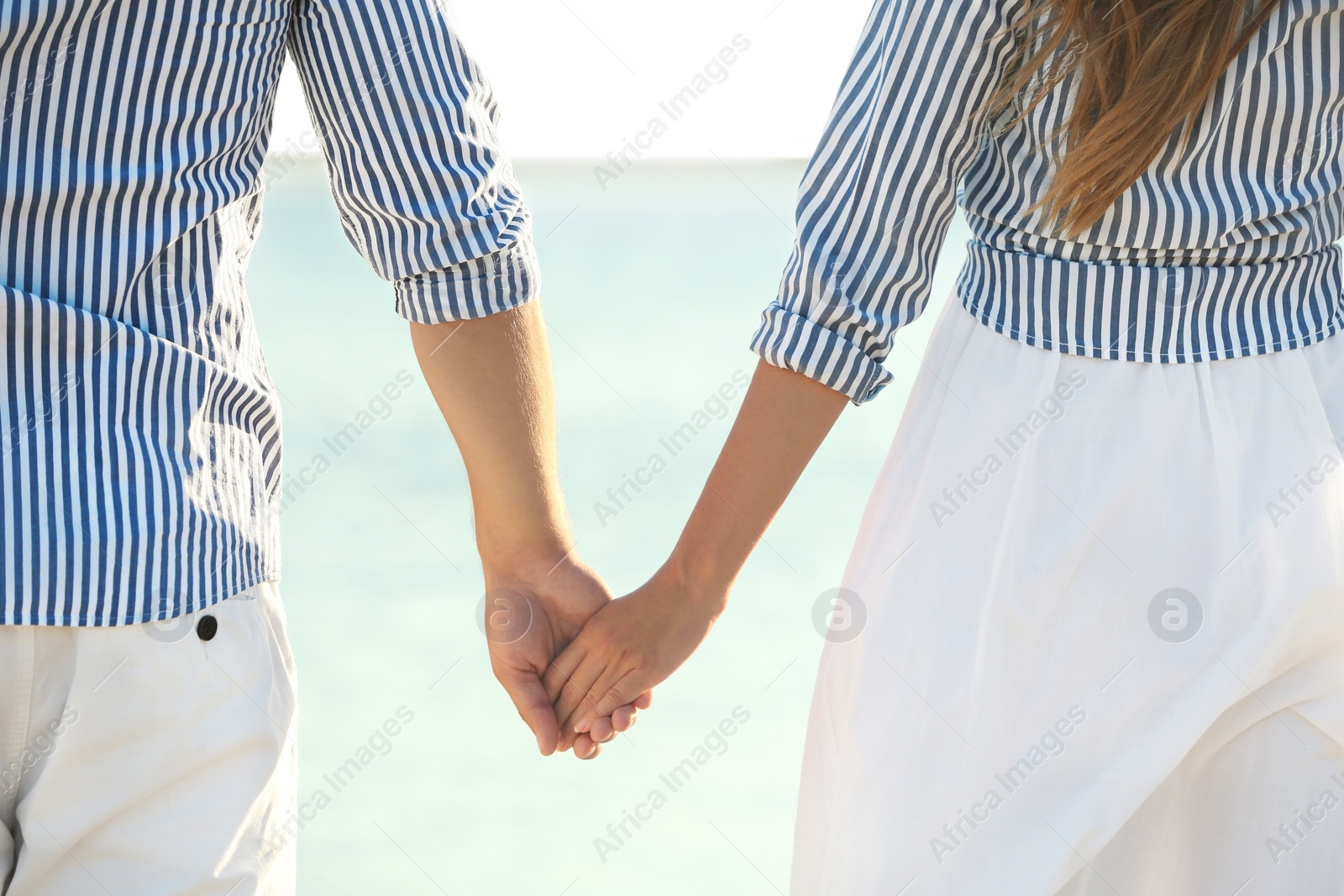 Photo of Happy young couple holding hands on beach, closeup