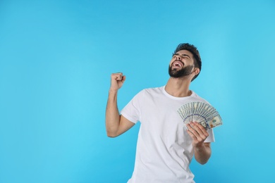Portrait of happy young man with money on color background. Space for text