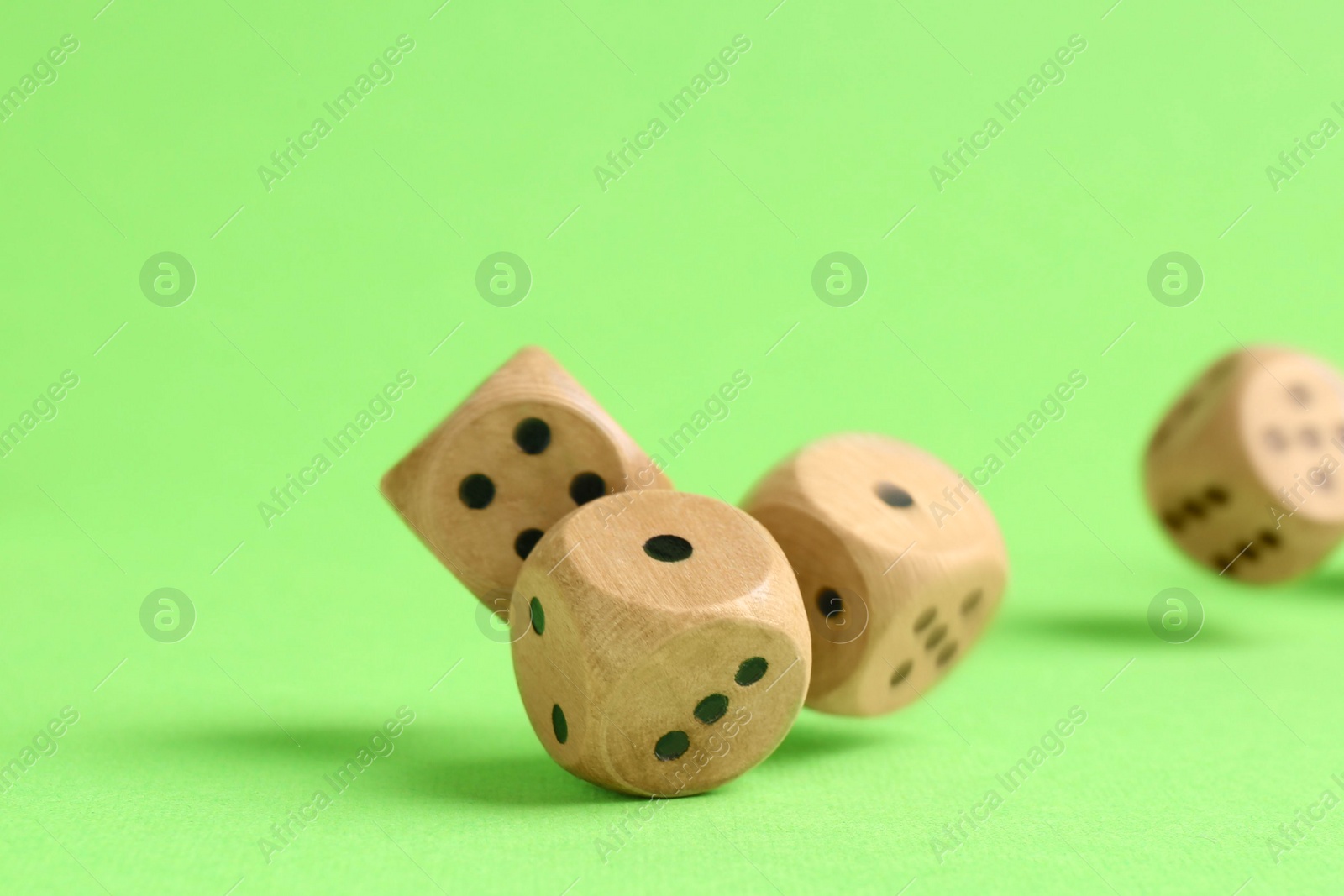 Photo of Many wooden game dices falling on green background, closeup