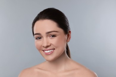 Photo of Portrait of attractive young woman with smooth skin on grey background