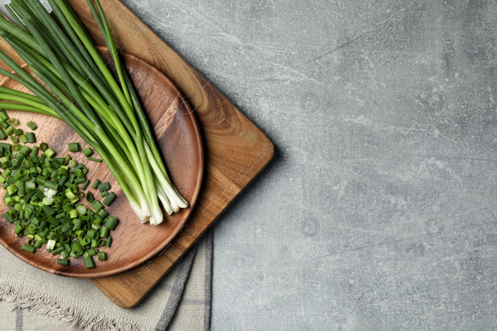 Photo of Chopped green spring onion and stems on grey table, top view. Space for text