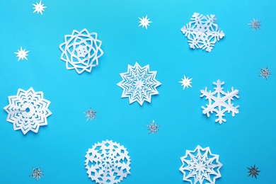 Photo of Flat lay composition with paper snowflakes on blue background. Winter season