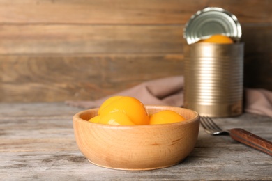 Photo of Bowl with canned peaches on wooden table