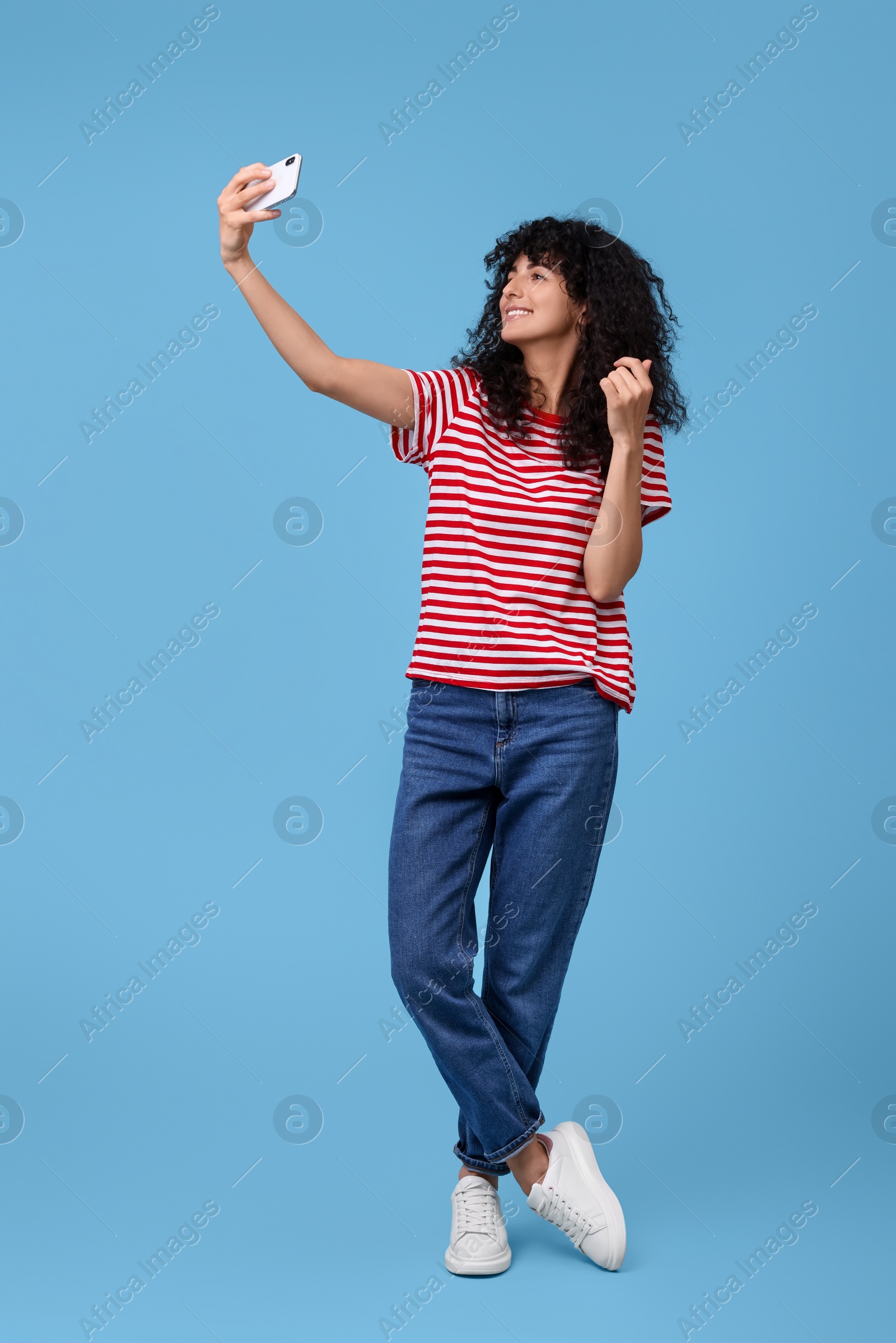 Photo of Beautiful young woman taking selfie on light blue background