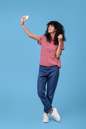 Photo of Beautiful young woman taking selfie on light blue background