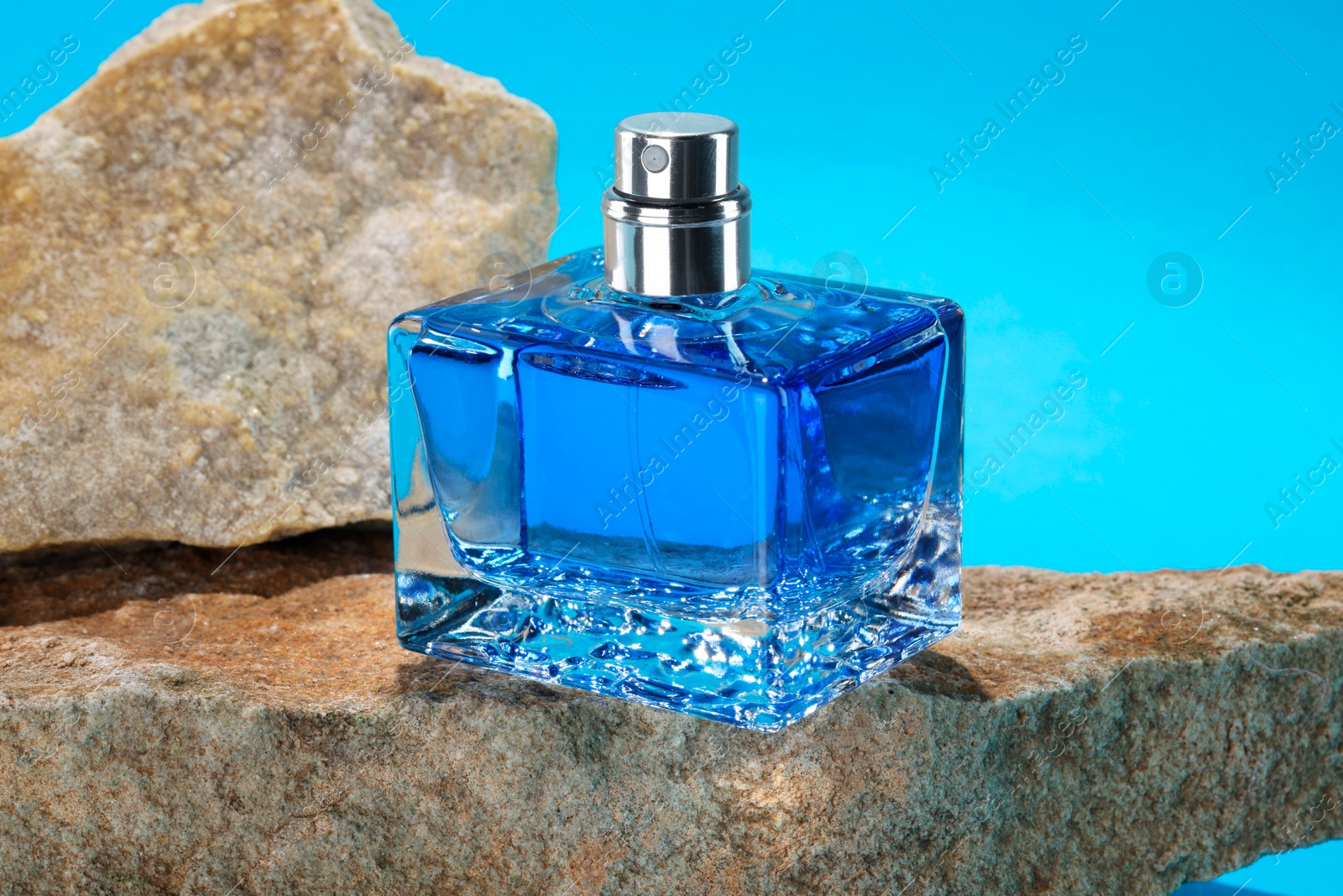 Photo of Stylish presentation of luxury men`s perfume on stones against light blue background