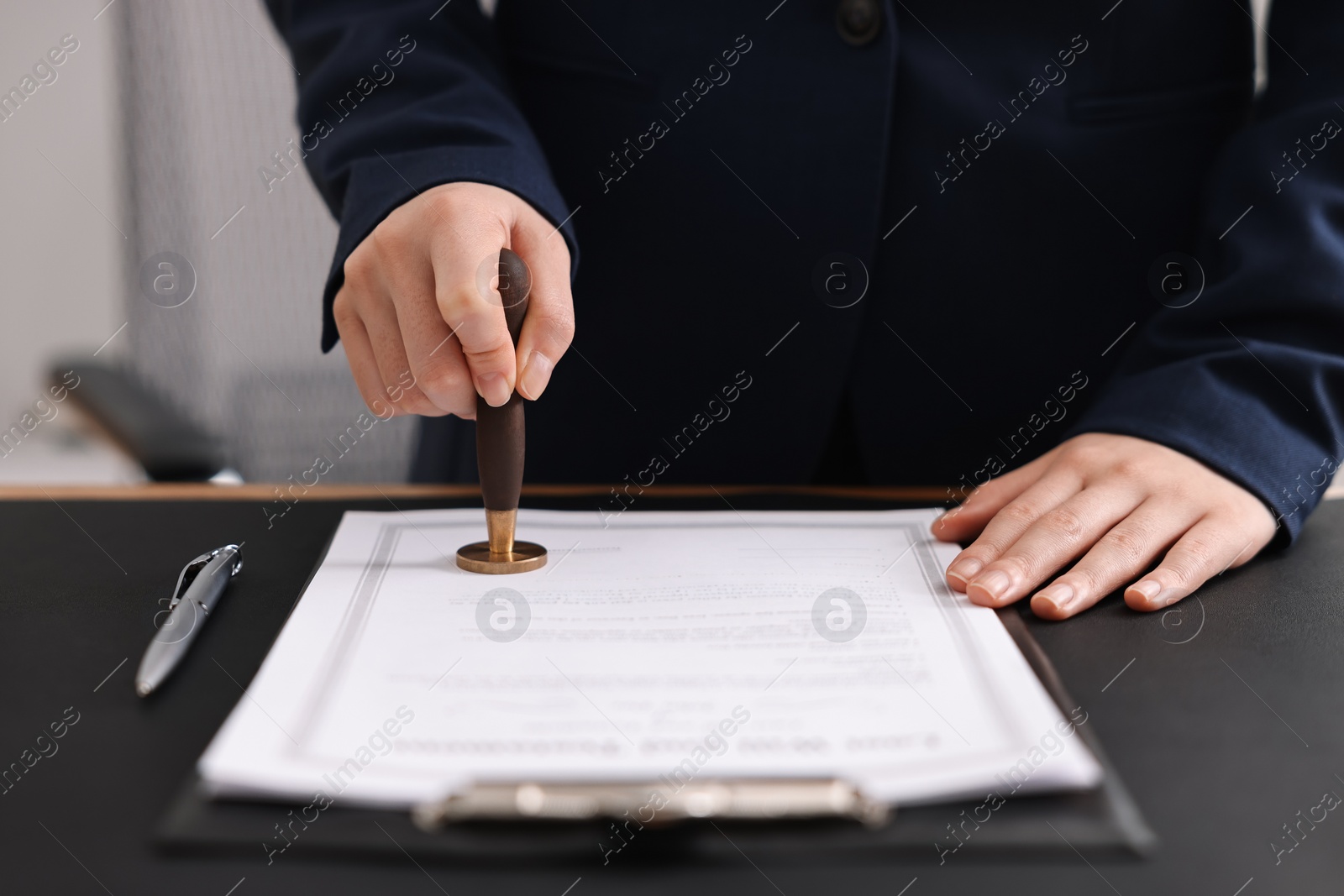 Photo of Notary sealing document at table in office, closeup