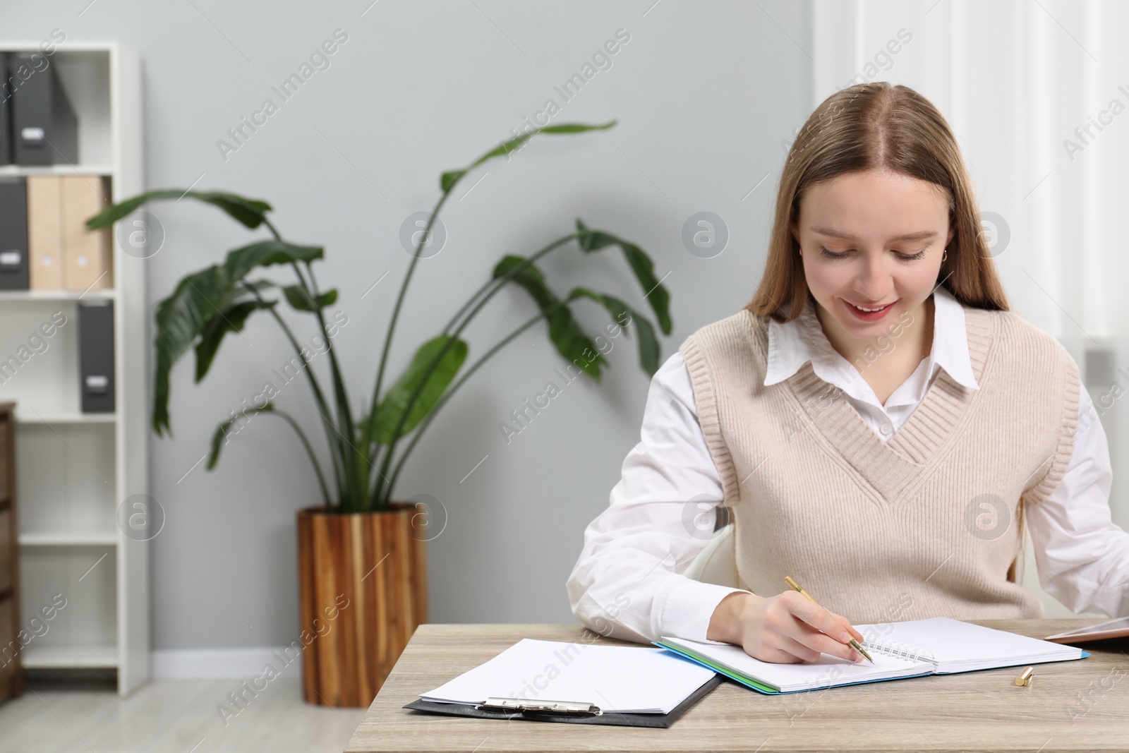 Photo of Woman taking notes at wooden table in office, space for text