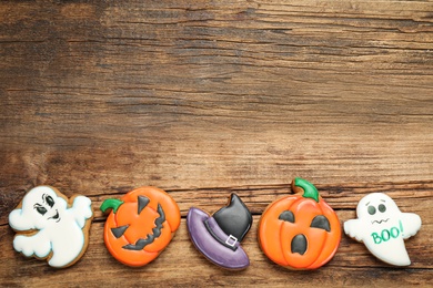 Photo of Tasty Halloween cookies on wooden table, flat lay. Space for text