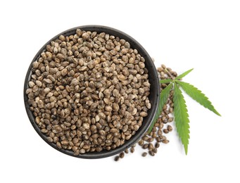 Bowl with hemp seeds and leaf on white background, top view