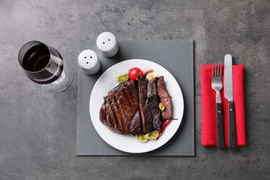 Photo of Delicious grilled beef meat served on grey table, flat lay
