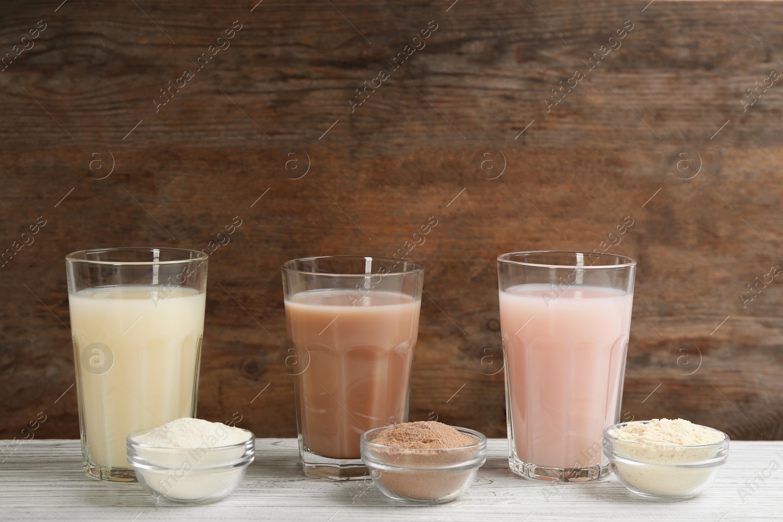 Photo of Protein shakes and powder on white wooden table