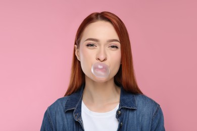 Portrait of beautiful woman blowing bubble gum on pink background