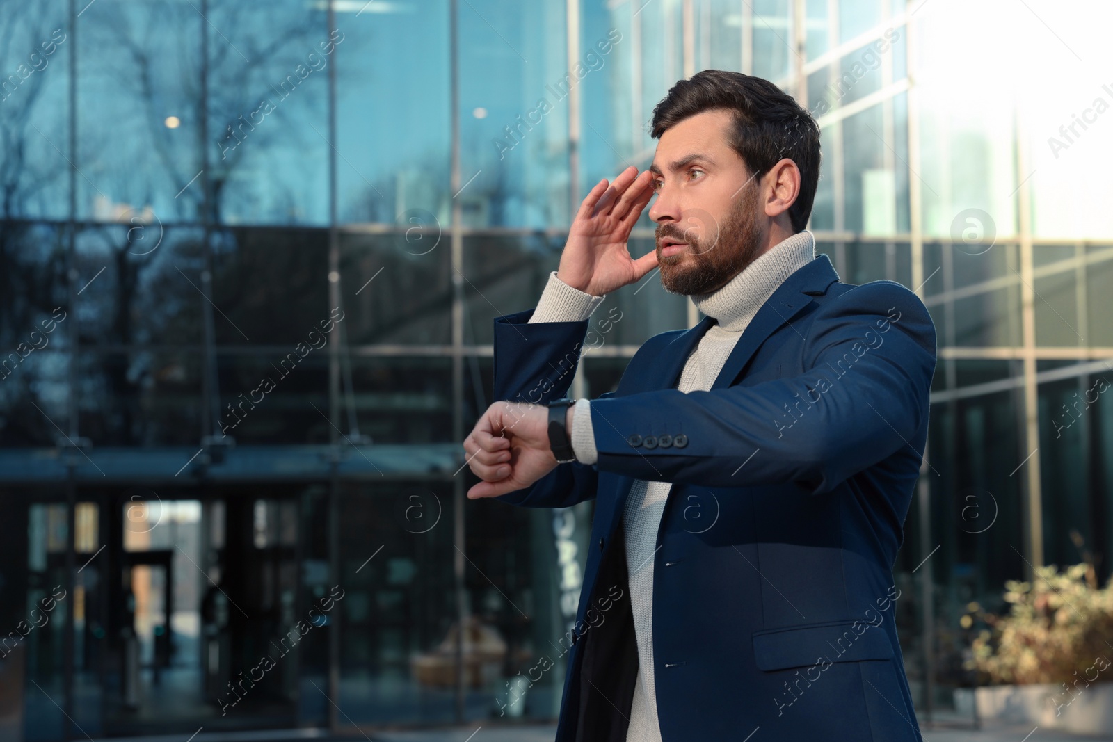 Photo of Businessman checking time on watch near building. Being late concept