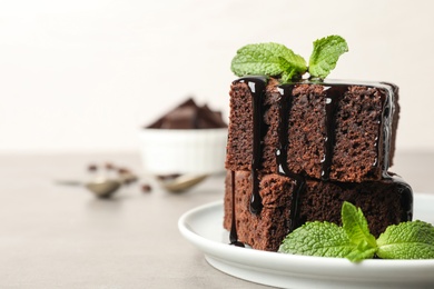 Photo of Fresh brownies with sauce and mint on table, space for text. Delicious chocolate pie