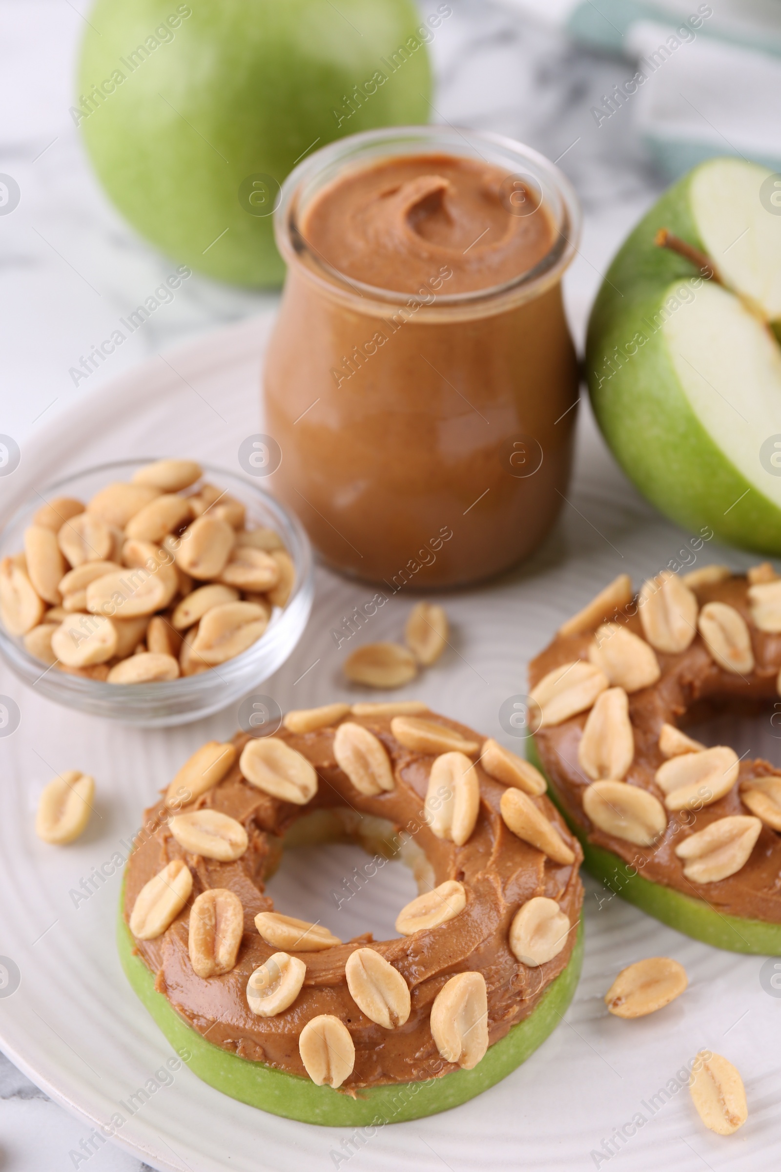 Photo of Fresh green apples with peanut butter and nuts on table, closeup