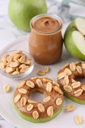 Photo of Fresh green apples with peanut butter and nuts on table, closeup