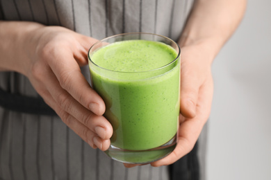 Photo of Woman holding tasty fresh kale smoothie, closeup