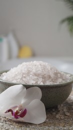 Photo of Bowl with bath salt and flower on wicker mat indoors