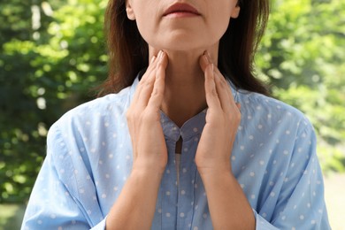 Mature woman doing thyroid self examination near window, closeup