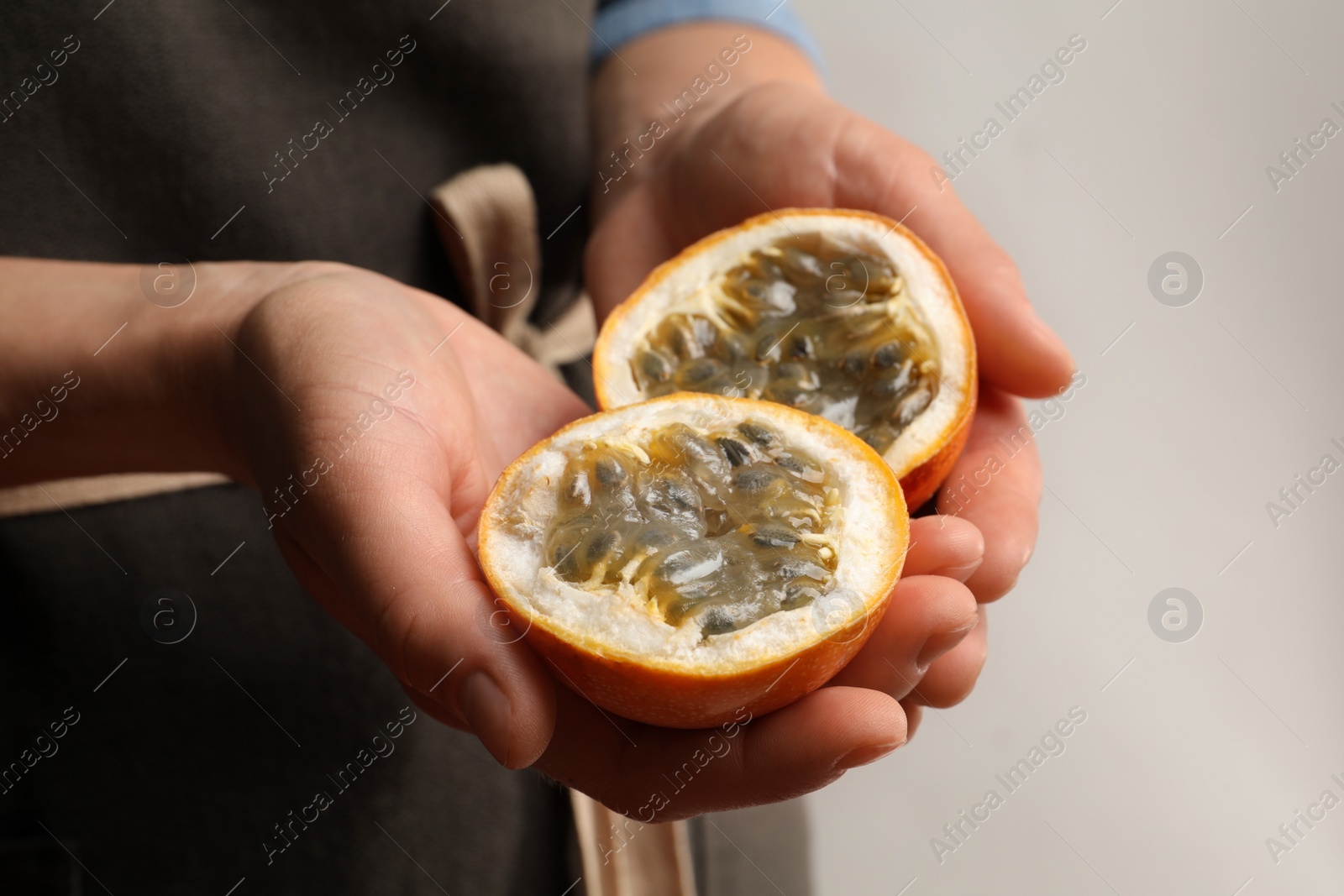 Photo of Woman with halves of granadilla on light background, closeup