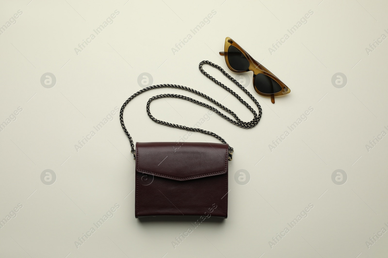 Photo of Stylish woman's bag and sunglasses on light  background, flat lay