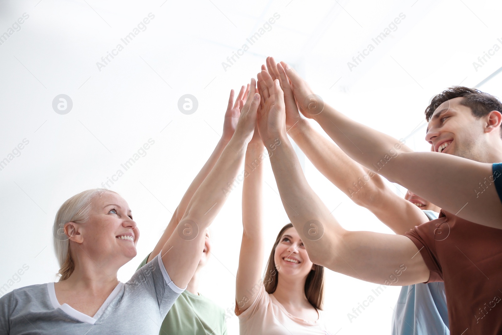 Photo of People putting hands together on light background. Unity concept