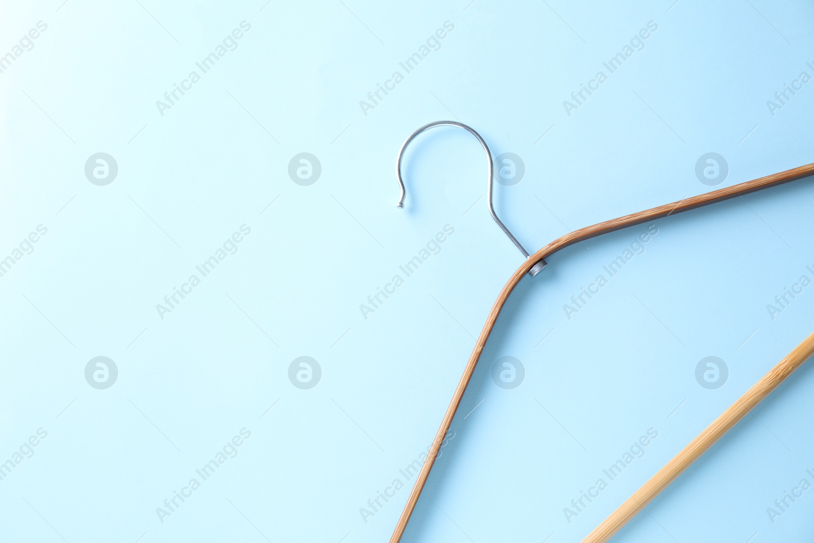 Photo of One wooden hanger on light blue background, top view. Space for text