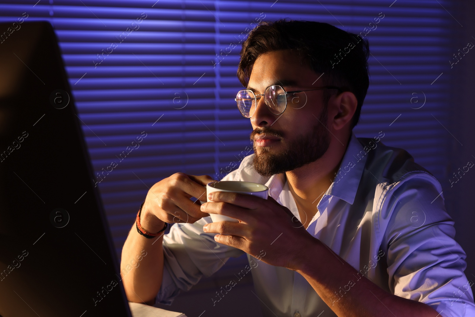 Photo of Tired man with coffee working late in office