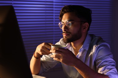 Photo of Tired man with coffee working late in office